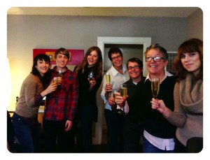 Uptown Studios Team Standing Holding Drinks Celebrating Thanksgiving In A Living Room