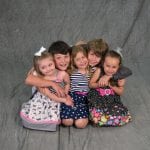 an image of 2 boys and 3 girls siblings kneeling on the ground and hugging each other