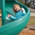 photo of a child on a slide in the playground
