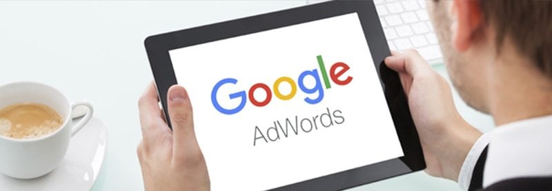 an over the shoulder shot of a man holding a tablet with the Google AdWords logo on it