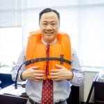 an image of a business man standing in his office and wearing an orange life jacket