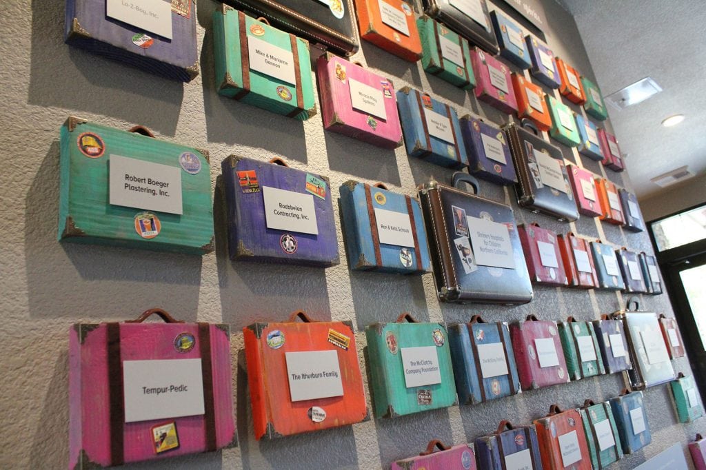 ronald mcdonald house donor wall with small suit cases with donor names or organization name on them
