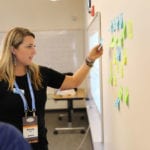 woman using post-it notes on board at conference