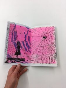 A pink print of spider webs and a silhouette of a girl being held by Jill