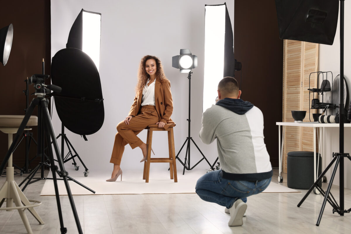 A woman in business casual attire having her photo taken on a professional photo set with many lights
