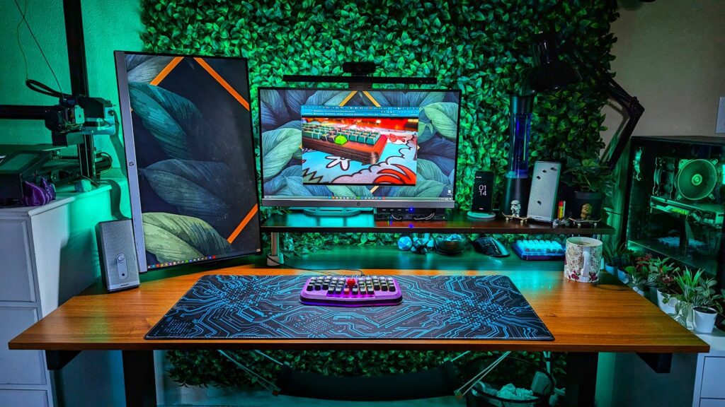 A desk with two monitors, a deskmat and and a keyboard