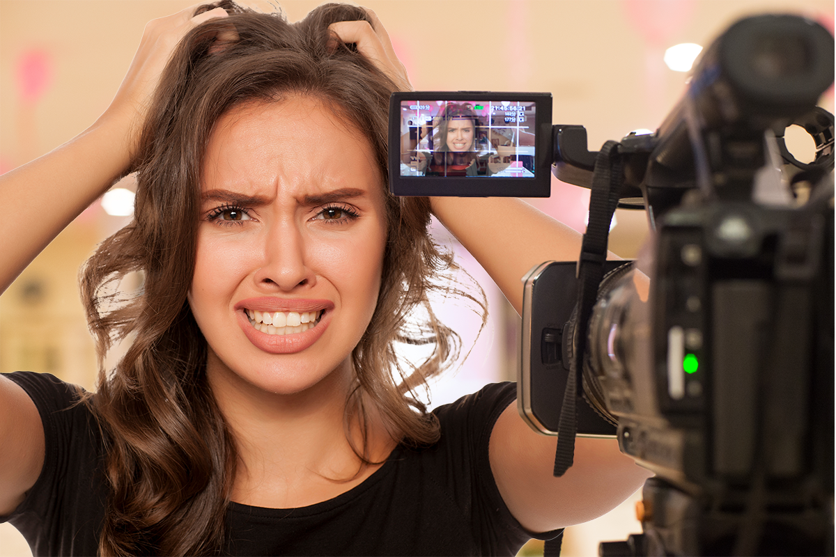 A woman looking frazzled and stressed out standing in front of a camera with a worried look on her face